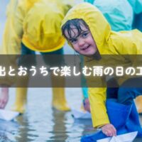 レインコート姿で水たまり遊びをする子ども